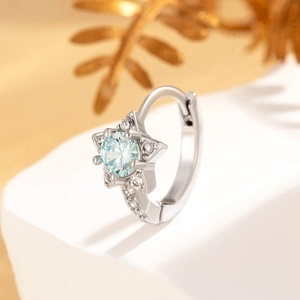 Star-shaped silver earrings with central blue zircon and sparkling crystals on stone base