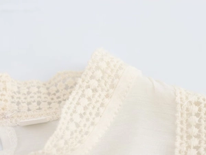 Close-up of cream lace trim and woven fabric details on long sleeve blouse shoulder