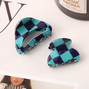 Detailed view of blue checkered acetate hair claws next to an elegant aroma bottle