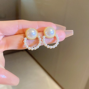 Detail of vintage gold pearl hoop earrings with a large stud and small pearl ring circle