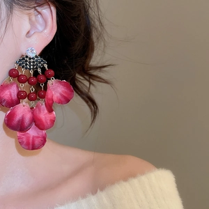 Detail of luxury fabric flower earrings with crystal tassels and deep red beads on a model