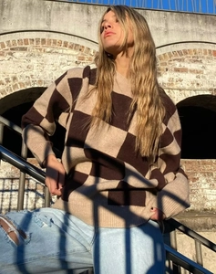 Detailed close-up of brown and beige checkerboard knit sweater with ribbed crew neck design