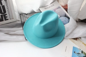 Flat lay of a turquoise wool fedora hat with stitched brim on a minimalist background