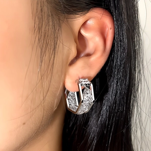 Dettaglio macro di orecchini geometrici in argento con zirconi scintillanti e design esagonale