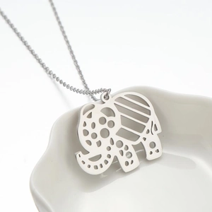Minimalist silver elephant pendant necklace with hollow pattern on ceramic tray