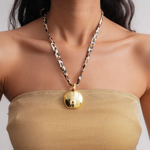 Détail d'un pendentif doré poli sur un cordon de collier en tissu à motif léopard
