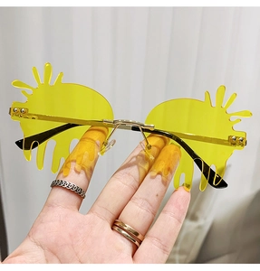 Detail of yellow teardrop-shaped rimless sunglasses with sunburst spikes and gold arms
