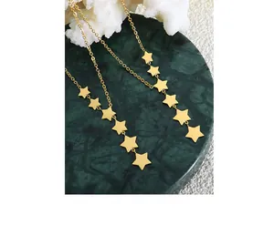 Close-up of gold star charms on a delicate chain necklace over green marble base