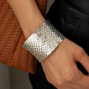 Macro shot of silver woven texture wide open bangle on wrist with stylish accessories