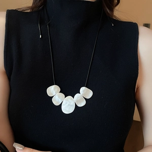 Irregular white geometric pendant on a minimalist black cord shown on model neck