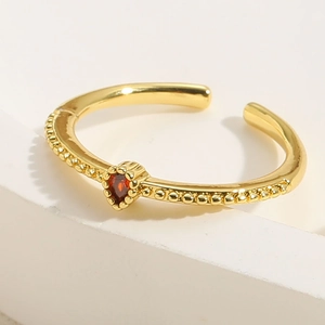 Macro shot of gold adjustable ring featuring a red heart zircon and beaded band detail