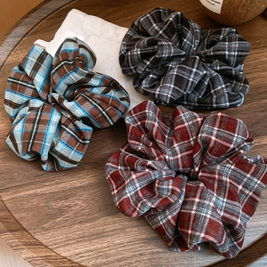 Detailed view of three plaid fabric scrunchies in blue, black, and red patterns