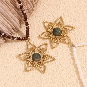Detail of 18K gold petal pendants with green natural stones on beaded necklaces