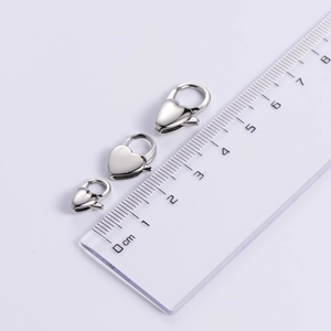 Detailed comparison of three heart-shaped stainless steel lobster clasps with a metric ruler