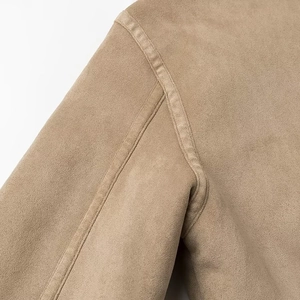Détail d'une veste en daim kaki montrant des coutures précises et une texture en peluche