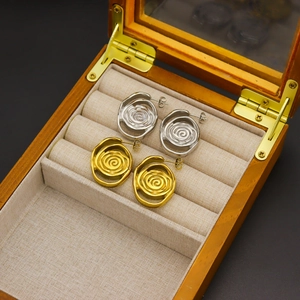 Elegant 18k gold and silver spiral rose petal stud earrings in a wooden jewelry box