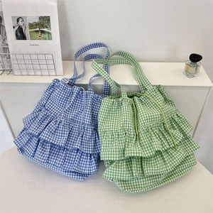 Detail of ruffled tiered layers on blue and green plaid canvas tote bags with fabric straps
