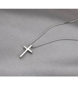 Detailed close-up of polished silver cross pendant on a delicate box chain necklace
