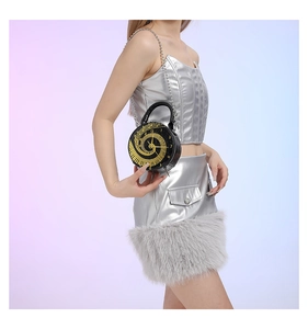 Close-up of a round clock-shaped handbag with gold dial detail and silver chain strap