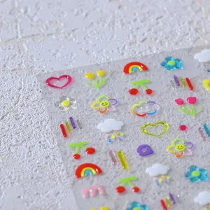Macro detail of 3D embossed nail stickers featuring colorful hearts and rainbow icons