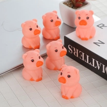 Group of six pink cartoon pig figurines displayed on a white checkered office desk