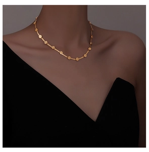 Detail of elegant gold snake chain choker with round discs on woman's collarbone