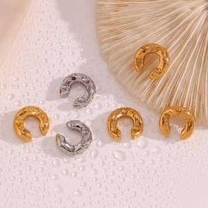 Macro shot of 18K gold and silver C-shaped chunky earrings with lava texture detail