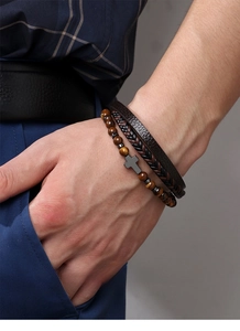Detail of a men's multilayered leather bracelet with tiger eye beads and cross pendant