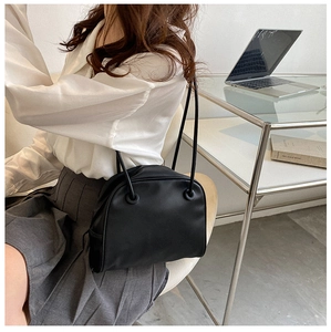Detailed view of black leather half-moon shoulder bag worn in a modern office setting