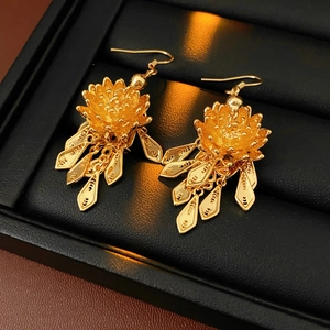 Detailed macro view of gold plated lotus earrings with long tassels on jewelry box