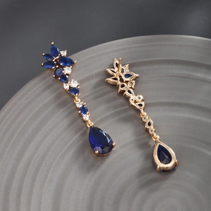 Macro detail of royal blue pear-cut gemstone drop earrings with elegant gold-tone setting
