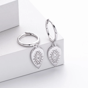 Macro detail of S925 silver hoop earrings with engraved eye pattern and small gemstone