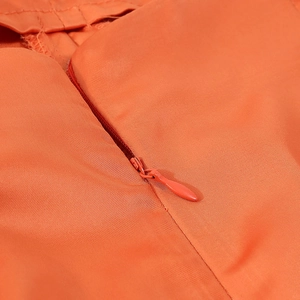 Détail d'une fermeture éclair invisible sur une combinaison orange vif texturée