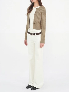 Brown cable knit cardigan paired with white trousers and a minimalist leather belt