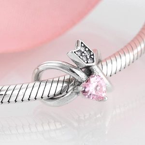 Macro shot of silver charm with pink heart gemstone on a snake chain bracelet