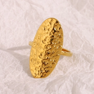 18K gold plated stainless steel ring with hammered oval surface on white textured paper