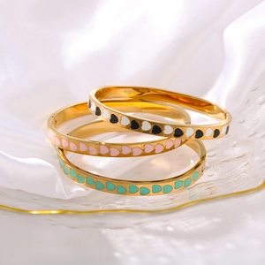 Three-piece set of 18K gold stainless steel heart enamel bangles on white silk fabric