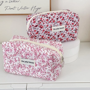 Detail of quilted floral makeup bags in red and pink colors with gold zipper closure