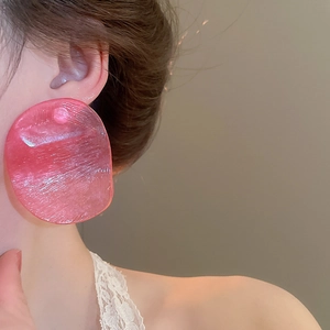 Side view of model wearing large oversized pink resin stud earrings with brushed texture