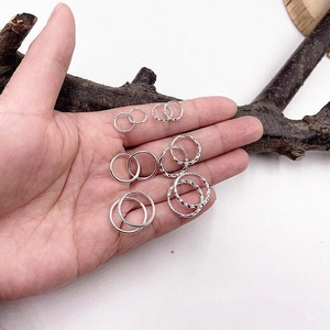 Detail view of various sizes of polished and twisted silver hoop earrings in hand