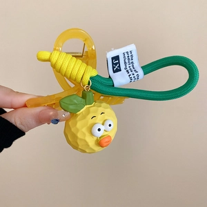 Detail of yellow resin hair claw featuring cute cartoon fruit charm and woven rope cord