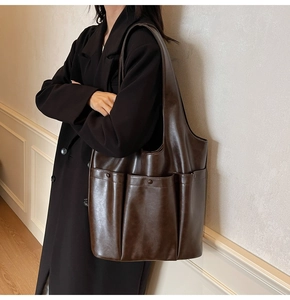 Macro detail of dark brown leather tote bag showing three functional front pockets