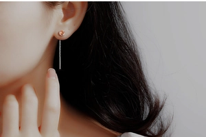 Detail of long silver chain earrings with champagne zircon stones on model ear