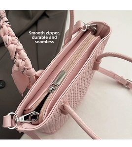Detail view of pink woven bag featuring smooth metal zipper and silk scarf handle