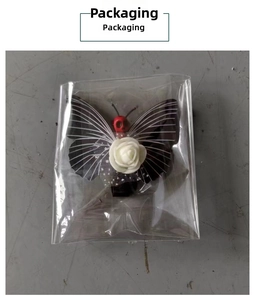 Gothic butterfly hair clip with white rose and red skull in protective packaging