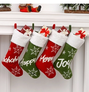 Detail of plush Christmas stockings in red and green with snowflake embroidery on fireplace