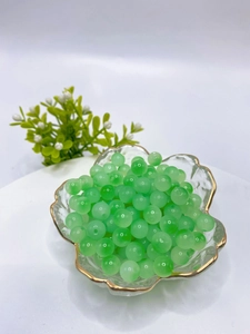 Detail view of 8mm green glass beads for DIY jewelry making in a decorative glass bowl