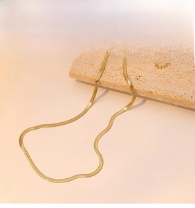 Close-up of elegant gold plated snake bone chain necklace displayed on stone pedestal