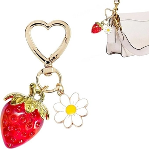 Chic strawberry and daisy keychain set with heart buckle shown on a beige handbag