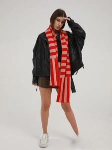Detailed view of long knit scarf featuring vibrant red and pink striped patterns
